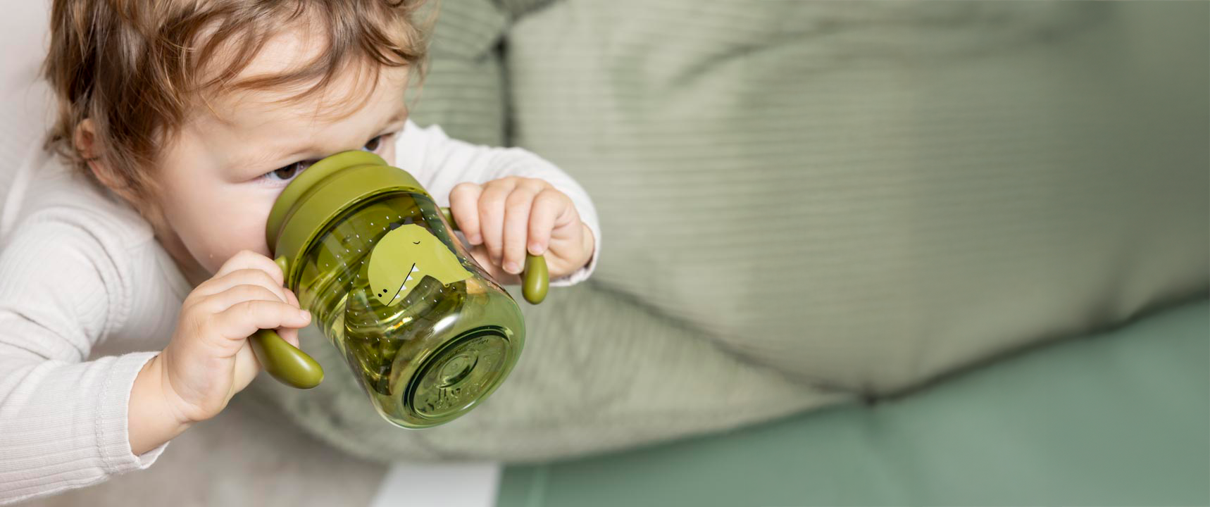 Child holding a training cup with drinkware promotional text.